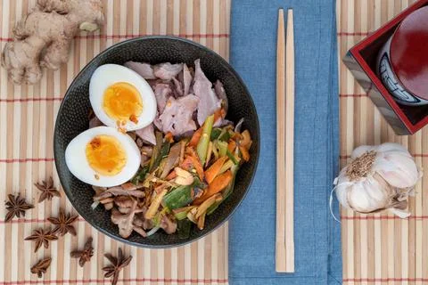 Top view studio shot of black bowl of ramen noodles with boiled eggs, veggies Stock Photos