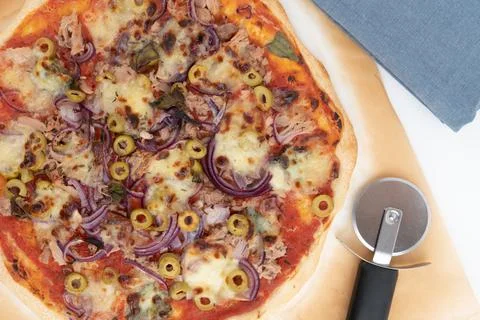 Top view studio shot of freshly baked pizza al tonno on baking paper, isolated Stock Photos