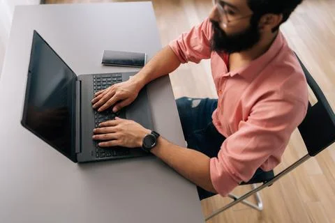 Top view of successful Indian programmer male in eyeglasses working on laptop Foto stock