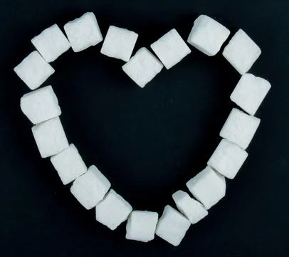 Top view of sugar cubes arranged in a shape of a heart on black background Stock Photos