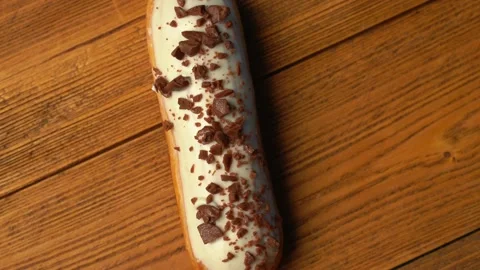 Top view of a sweet eclair with chocolate sprinkles rotating on a wooden table Stock-Footage 204909924