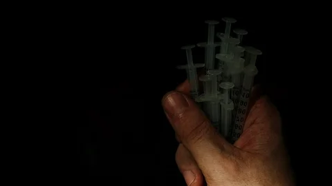 TOP VIEW: Syringes fall from the hand Vídeos de archivo 99082556