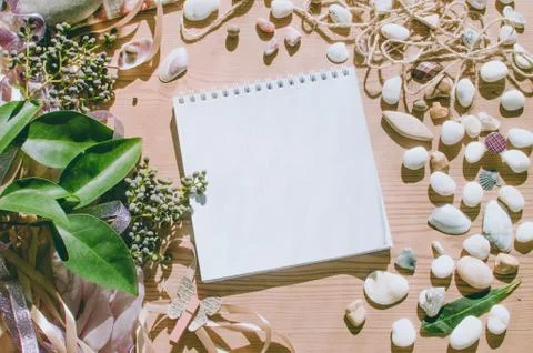 Top view on the table. Romantic desk. Notebook, sea stones, design items. Stock Photos