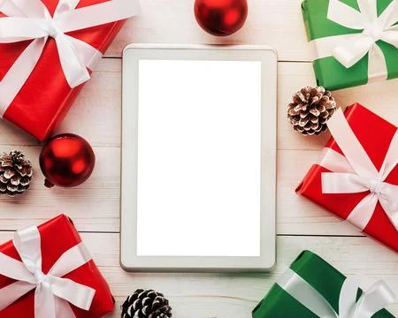 Top view of a tablet computer on a table, surrounded by festive gift boxes and C Stock-Fotos