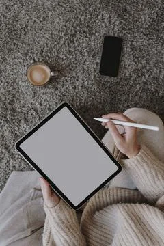 Top view tablet mockup with copy space. Woman wearing beige clothes sitting o Stock Photos