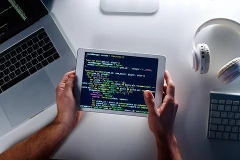 Top view of tablet screen with coded data held by male programmer Stock Photos