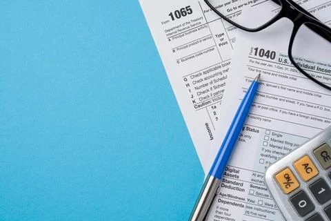 Top view of tax forms, calculator and pen on blue table Stock Photos