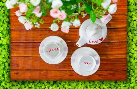 Top view of the teapot, empty  teacup and artificial flowers on a wooden and Stock Photos