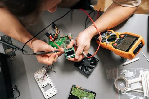 Top view of technician using multimeter to diagnose electronic circuit board Stock Photos