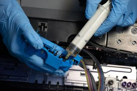 Top view of a technician using a vacuum cleaner to suck ink from a printer. Stock Photos