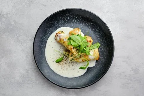Top view of thin crepe stuffed with cheese, arugula and spinach on a plate wi Foto stock
