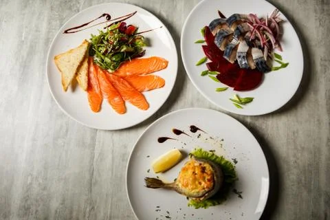 Top view on three assorted restaurant dishes of mackerel, salmon, and trout a Фото