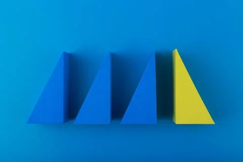 Top view of three blue and one yellow triangles against blue background Stock Photos