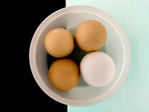 Top view of three brown eggs and one white egg in white plastic box. Isolated Stock Photos
