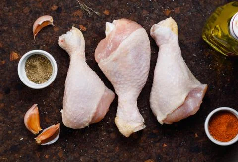 Top view on three chicken raw fresh legs on a dark cork rustic table Stock Photos