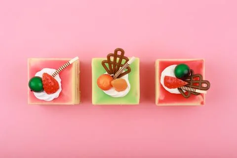 Top view of three colorful mini cakes on bright pink background Stock Photos