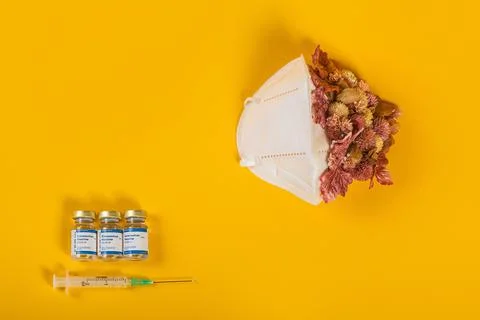 Top View Of Three Coronavirus Vials And Syringe With Medical Mask Pink Flowers Stock Photos