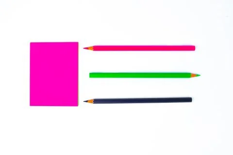 Top view of three different colored wood pencil crayons pointing at a pink st Stock Photos