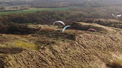 Top view of three Dutch paragliders soaring along vegetated coastal dune Stockbeeldmateriaal 323787319
