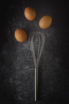 Top view three eggs and egg whisk on grunge background Stock Photos
