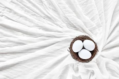 Top view of three light blue easter eggs in the nest on white elegant texti.. Stock Photos