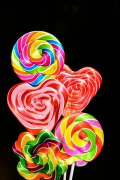 Top view of three multicolored lollipops isolated on dark blue background. Pi Stock Photos