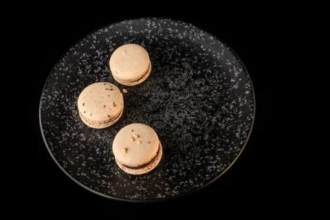 Top view three peanut macarons with chocolate filling on black plate 写真素材