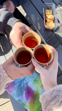 Top view of three people clinking paper cups with tea in a toast during a s.. Fotos Stock