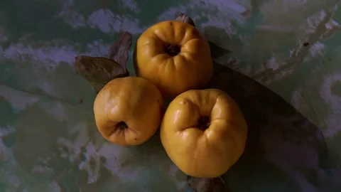 Top view of three ripe yellow quinces with dry leaves on a green textured marble Stock Footage 341888094