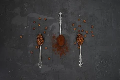 Top view of three spoons with coffee and coffee beans on black background. Stock Photos