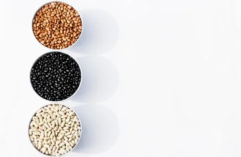Top view of three varieties of beans in bowls, white background Stock-Fotos