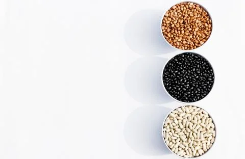 Top view of three varieties of beans in bowls, white background Stock Photos