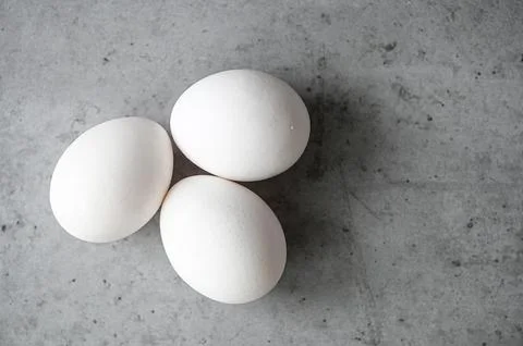 Top view of three white eggs on gray table Foto stock