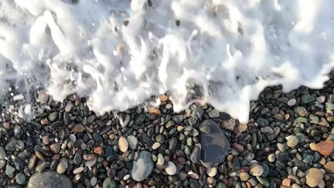 Top view. Tide. Sea wave with foam on pebble beach Stock Footage 263447529