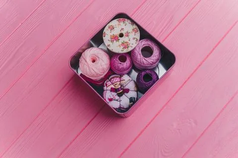 A top view of a tin box containing vibrant yarn and sewing items, placed on.. Stock Photos