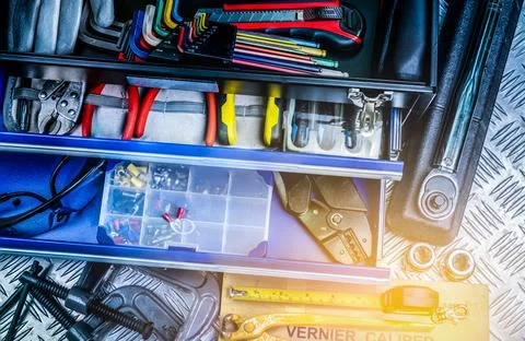 Top view of tools in box on checkered plate background in workshop. Service.. Stock Photos