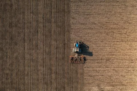 Top view of a tractor harrowing soil on an agriculture field. Acricultural ti Stock Photos