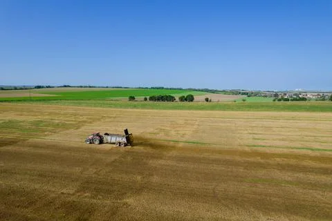 Top view of a tractor scattering manure on a field from a trailer. Rural loca Stock Photos