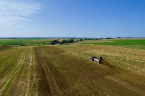Top view of a tractor scattering manure from a trailer in the field. Fertiliz Stock Photos