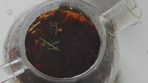 Top view of a transparent glass teapot being filled with hot water. Loose leaf Stock Footage 346547448