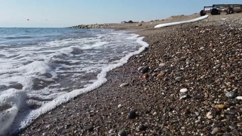 Top view, transparent waves wash the sand and pebble beach. Stock Footage 202242423