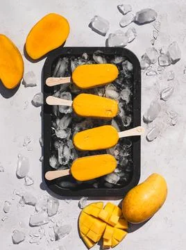 Top view of tray of mango popsicles on white background in sun. Stock Photos
