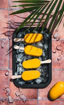 Top view of tray of mango popsicles on terra cotta tile in sun. Stock Photos