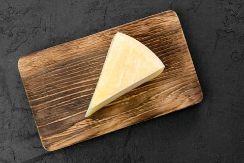 Top view of triangular piece of goat cheese on wooden cutting board Stock Photos