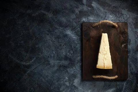 Top view of triangular piece of hard cheese on wooden cutting board Stock Photos