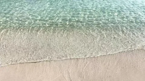 Top view turquoise waves gently lapping a sandy beach Видео 348067990