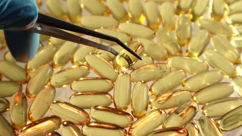 Top view as tweezers sort through capsules of Omega 3 fish oil Stock Footage 312988396