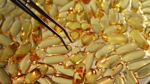 Top view as tweezers sort through capsules of Omega 3 fish oil	 Video stock 312988399