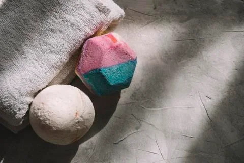 Top view of two bath bombs placed next to a white towel on a gray surface wit Stock Photos