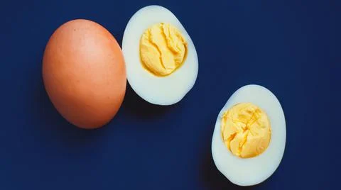Top view of two boiled eggs, one egg still in the shell, and the other egg pe Stock Photos